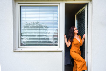Fototapeta na wymiar young woman opens pvc balcony door with jalousie near pvc window