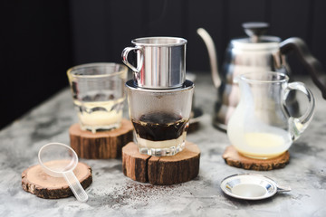 Preparing Vietnamese pour over coffee with condensed milk. Brewed coffee dripping into glass from...