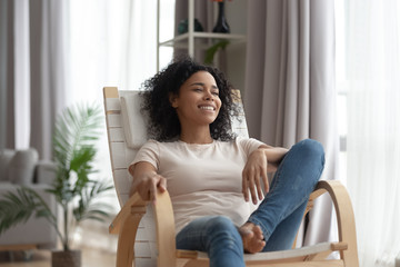 Smiling calm black woman relaxing in comfortable wooden rocking chair