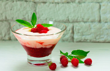  Yogurt with berry mousse decorated with raspberries and mint on a white table.