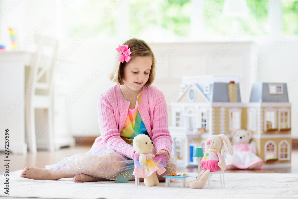 Wall mural Little girl playing with doll house. Kid with toys