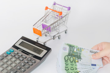 Euro banknotes with calculator and shopping basket background. - 277237759