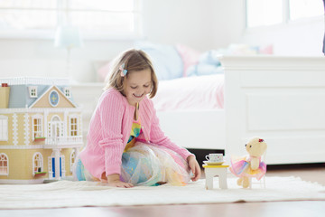 Little girl playing with doll house. Kid with toys