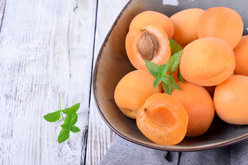 Ripe apricots in a ceramic bowl on the white table