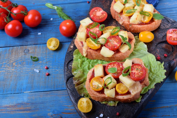 Bruschetta with different sorts of cherry tomatoes and soft cheese on the blue table