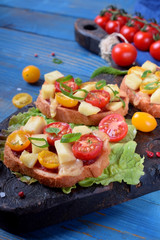 Bruschetta with different sorts of cherry tomatoes and soft cheese on the blue table