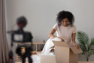 Happy african young woman blogger open parcel shooting vlog