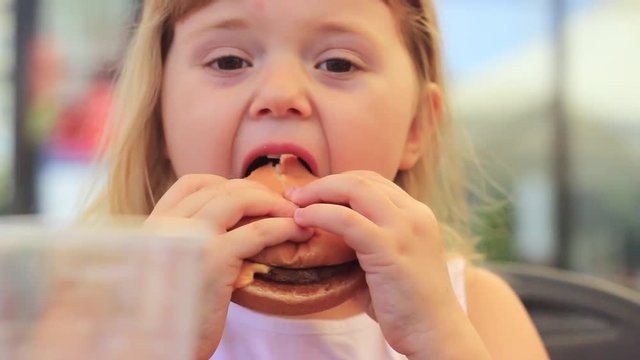 Close up of a little girl eating her cheeseburger