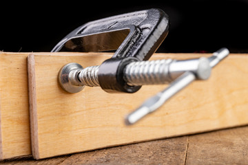 A small joinery clamp used for gluing planks. Accessories for carpenters on the workshop table.