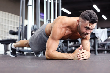 Fototapeta na wymiar Portrait of a fitness man doing planking exercise in gym.