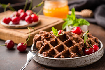 Chocolate belgian waffles with cherries and honey on a plate. Whole wheat waffles, healthy breakfast or dessert concept