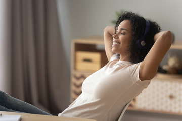 Happy african girl wearing headphones relaxing listening to music