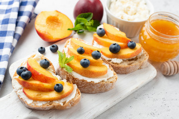 Fototapeta na wymiar Tasty Fruit Bruschetta With Peach Ricotta Cheese Berries And Honey On Serving Board