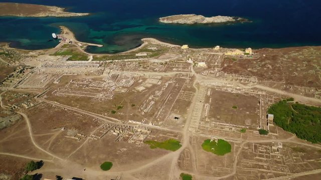 Aerial drone panoramic distant view video of famous archaeological site a whole ancient citadel in island of Delos, Cyclades, Greece