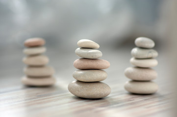 Harmony and balance, three cairns, simple poise pebbles on wooden light white gray background, simplicity rock zen sculpture