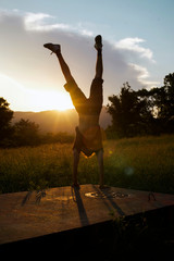 Young man doing a handstand at sunset 