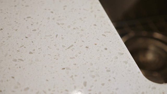 Kitchen Sink Detail Rack Focus Countertop. view moves right on a granite countertop detail and racks focus to the sink basin