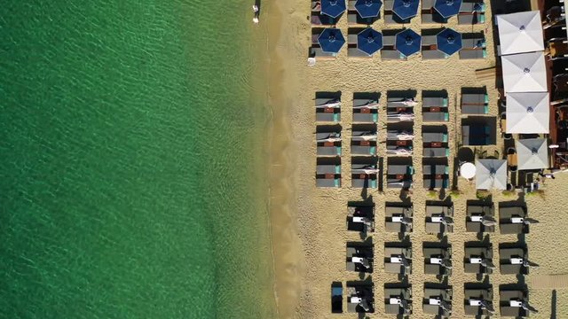 Aerial drone video of famous celebrity sandy beach and bay of Ornos with crystal clear emerald sea, Mykonos island, Cyclades, Greece