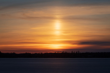 Light pillar in colorful sunset clouds