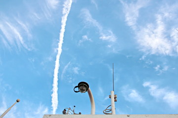 Blue sky and clouds in the open ocean. Views of the ship's mast and antennas on the navigation deck.