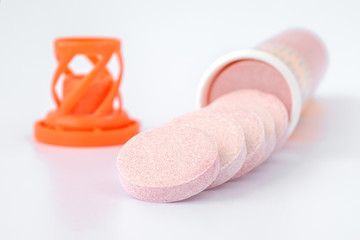 Soluble effervescent vitamin tablets spilled out of a plastic bottle on a white background....
