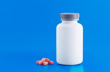 A white bottle of medicine,pink tablets on a blue background,modern medicine used for the prevention and treatment of diseases, copies the space.