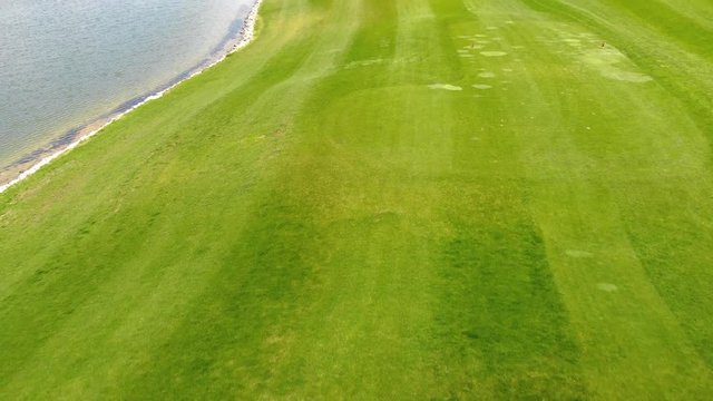 Golfer In Tee Box Driving Ball Aerial Follow. an aerial view of a golfer taking a swing on a whole and view moves over as he strikes the ball