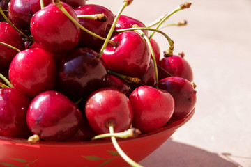 Close up of pile of ripe cherries with stalks and leaves. Large collection of fresh red cherries.