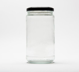 Empty glass jar with a black lid on white background.