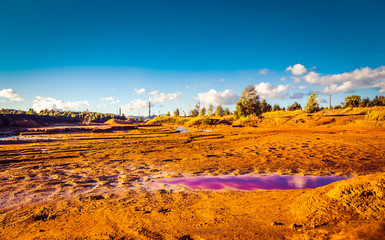 River with polluted red toxic water and soil and with garbage on the shore. environmental pollution by the factory