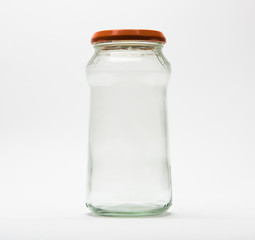 Empty glass jar with an orange lid on white background.