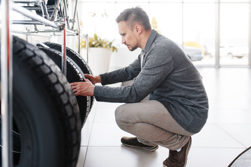 Man choosing tyres for new car in showroom