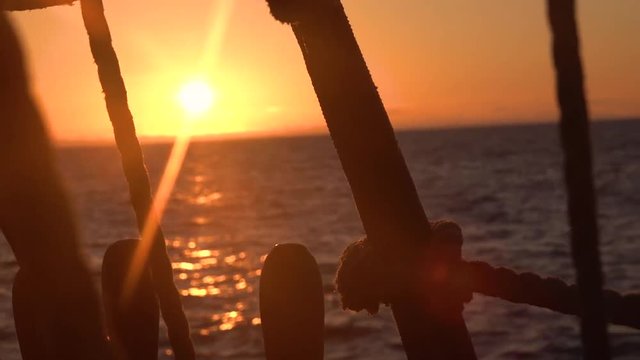 Sunset through the shrouds and rigging of an old sailing vessel.