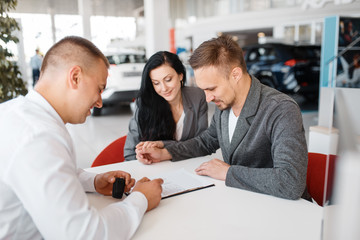 Salesman and couple make out the sale of a new car