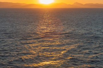 Sunset with reflections over the sea with islands of Saronic Gulf background