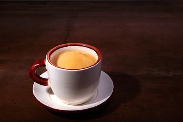 A cup of espresso coffee on a dark wooden background