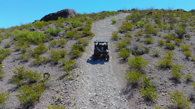 Aerial Follow ATV Up a Trail. aerial view follows a side-by-side terrain vehicle up a mountain trail