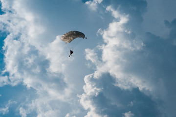 Skydiver with parachute on epic clouds and blue sky background. Copy space