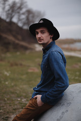 Young caucasian man with black rounded hat in the mood nature. Hipster farmer concept