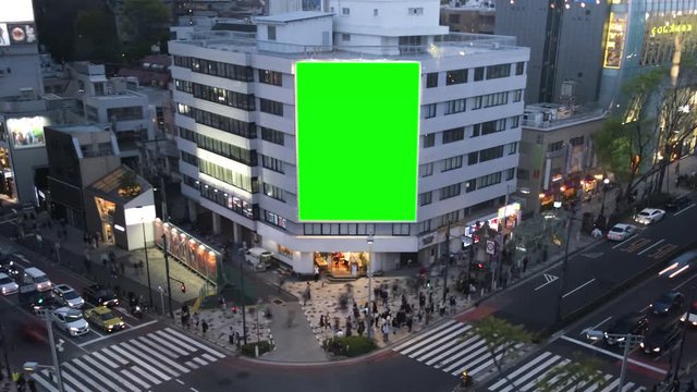 Large billboard with a green screen, on the modern building, busy crossroad with neon lights, timelapse of traffic, Tokyo, Japan