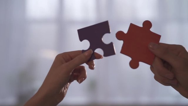 Business people join puzzle pieces in office. Concept of teamwork and partnership