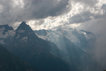 Panorama of misty mountains scene with dramatic sky in national park of Dombay