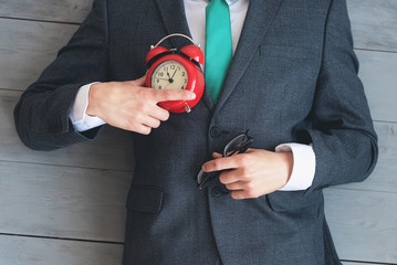 Tired overworked businessman with a red alarm clock in his hand is sleeping on an office floor...