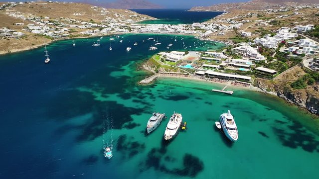 Aerial drone, bird's eye view photo of famous crowded full of sun beds turquoise colour sandy beach of Ornos, Mykonos island, Cyclades, Greece