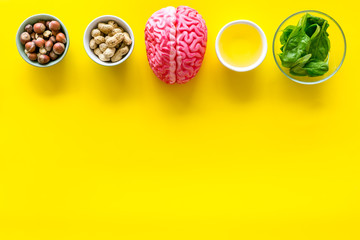 Proper nutrition for brain with nuts, spinage and oil stethoscope on yellow background top view copy space