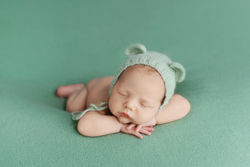Sleeping newborn baby on a green background. Photoshoot for the newborn. A few days from birth.