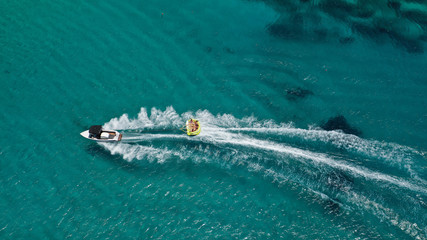Naklejka premium Aerial drone photo of extreme powerboat donut watersports crusing in high speed in famous sandy beach of Platy Gialos, Mykonos island, Cyclades, Greece