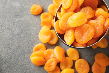 Bowl with dried apricots on grey background