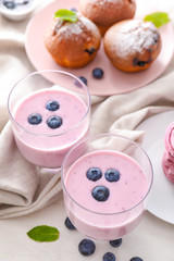 Fototapeta na wymiar Glasses of tasty blueberry yogurt on white table