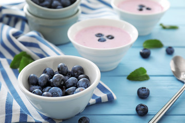 Bowls with tasty blueberry and yogurt on table
